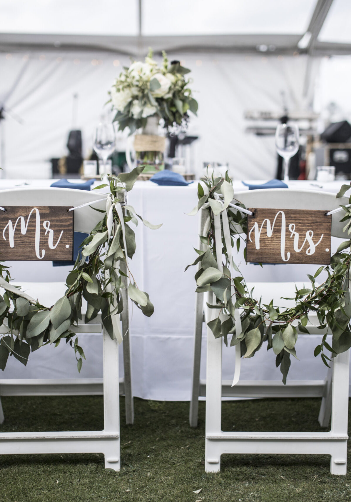 Wedding table under tent, with Mr and Mrs signs on the chairs